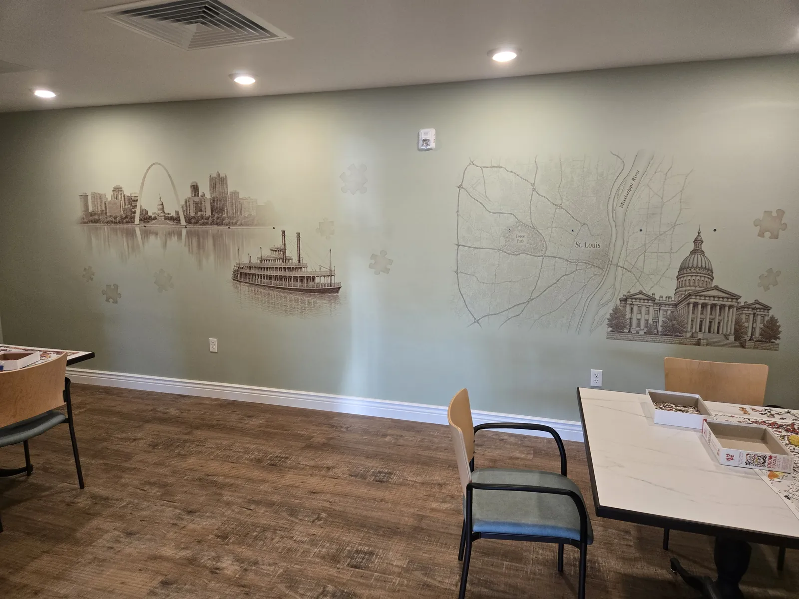 St. Louis Scenes mural wall by Deana Dods with Gateway Arch skyline, riverboat, city map, and Old Courthouse installed in a community puzzle room